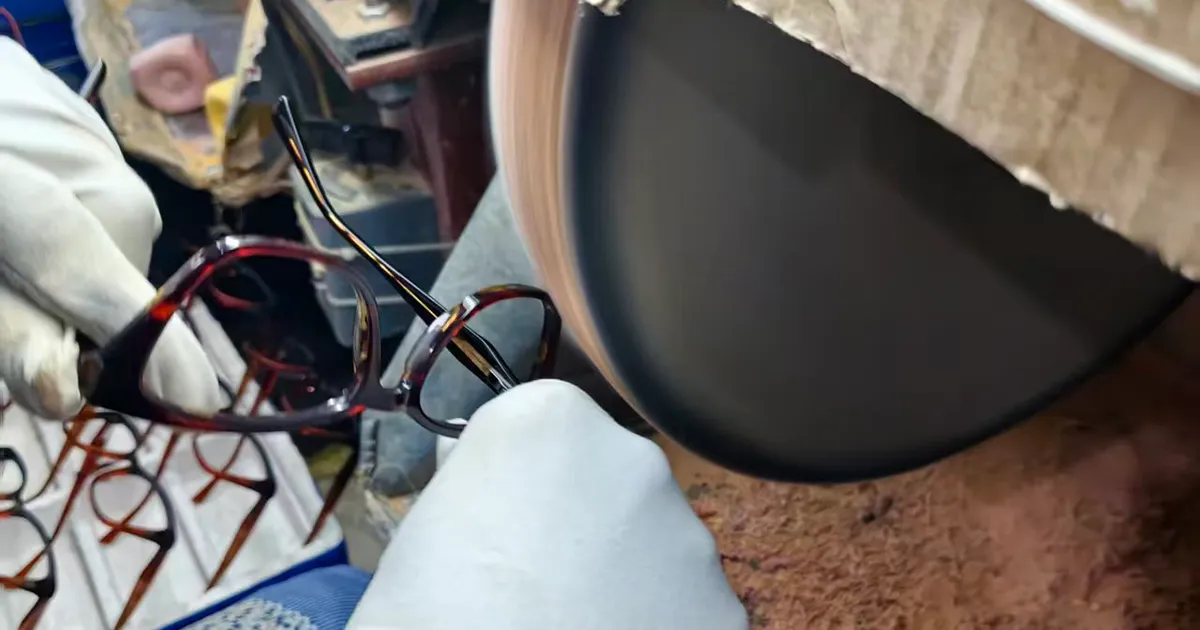 Hand polishing an acetate frame on the buffing wheel at the VISTALUMO factory in Yiwu