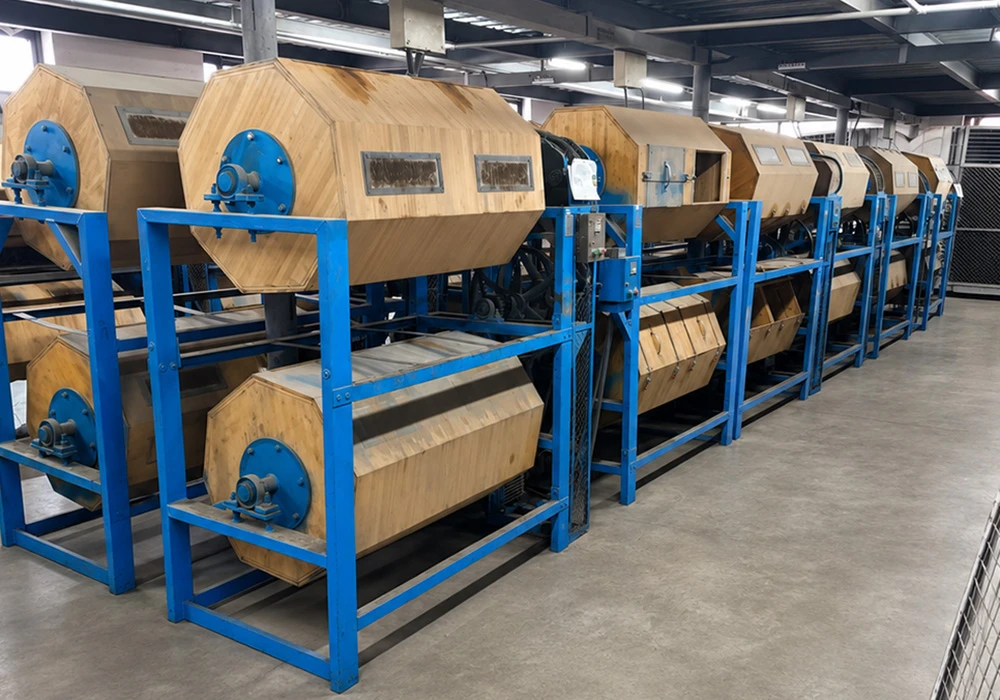 Row of wooden tumble polishing drums for acetate frame finishing at VISTALUMO factory